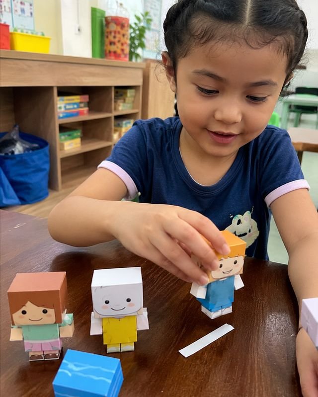 Niña jugando con personajes de papel 3D